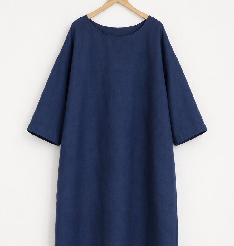 Dunkelblaues Kleid Nr. 4 aus Webware auf einem Holzbügel vor einer weißen Wand, mit überschnittenen Schultern und weiten Dreiviertelärmeln.