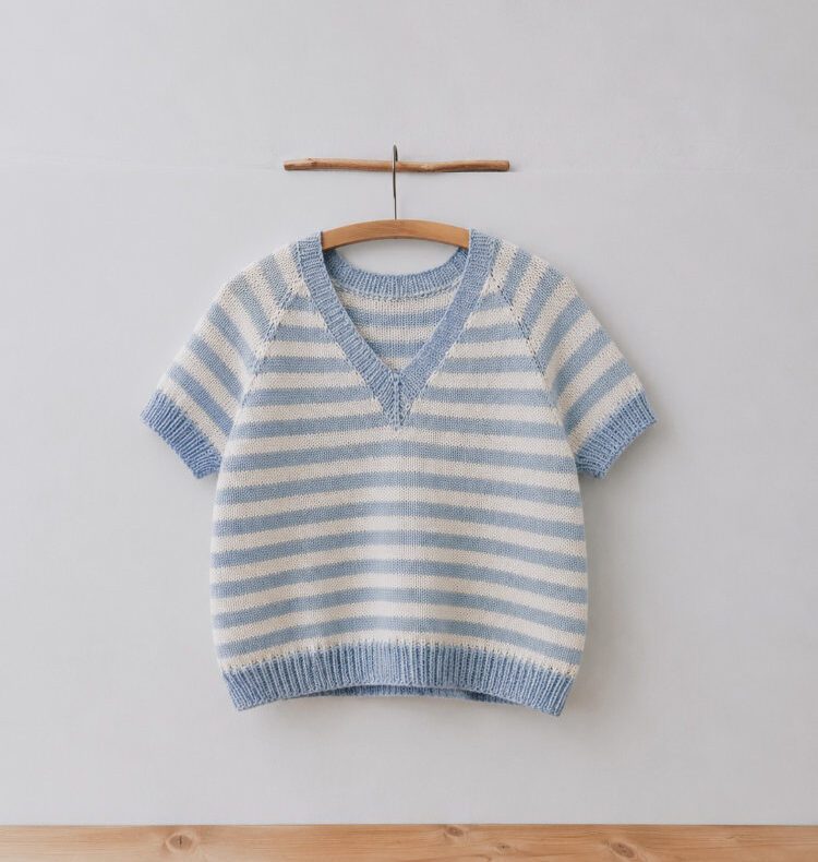 gestreifte Koora Blouse mit kurzen Ärmeln in Hellblau-Weiß, an einer Wand hängend