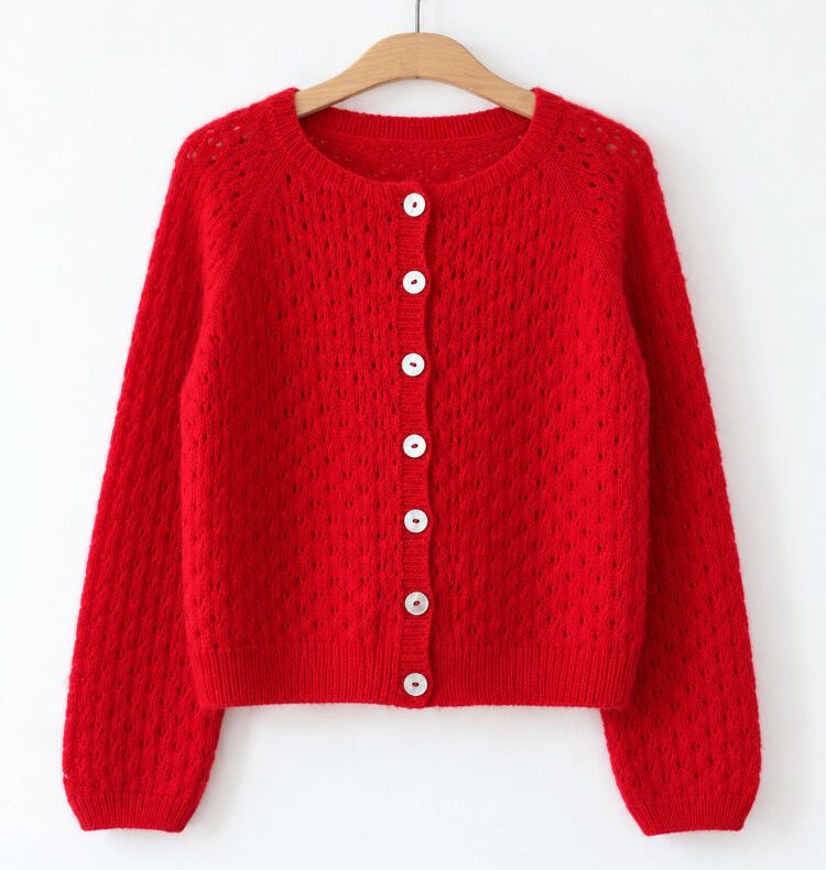 Miyaar Cardigan in Rot mit durchgehendem Lace-Muster, Raglankonstruktion, Rundhalsausschnitt und schmalen Bündchen am Holzbügel.
