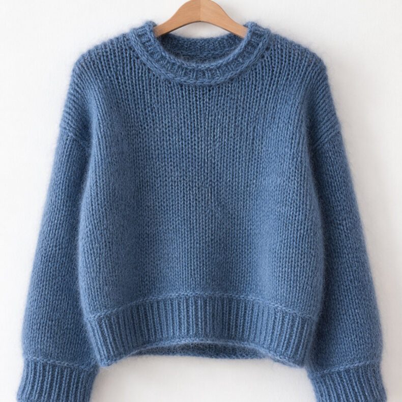 Heedi Sweater aus Merino und Mohair in Jeansblau, nahtlos von oben nach unten gestrickter Pullover mit Rundhalsausschnitt, leicht verkürzter Vorderlänge, überschnittenen Schultern und markanten querliegenden Maschen vor Saum- und Ärmelbündchen.