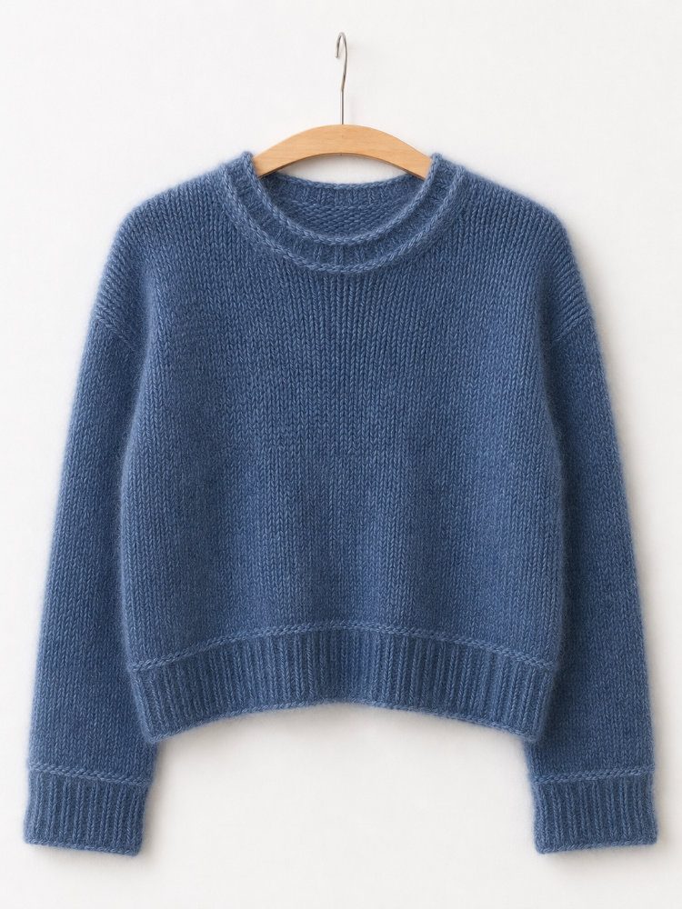 Heedi Sweater aus Merino und Mohair in Jeansblau, nahtlos von oben nach unten gestrickter Pullover mit Rundhalsausschnitt, leicht verkürzter Vorderlänge, überschnittenen Schultern und markanten querliegenden Maschen vor Saum- und Ärmelbündchen.