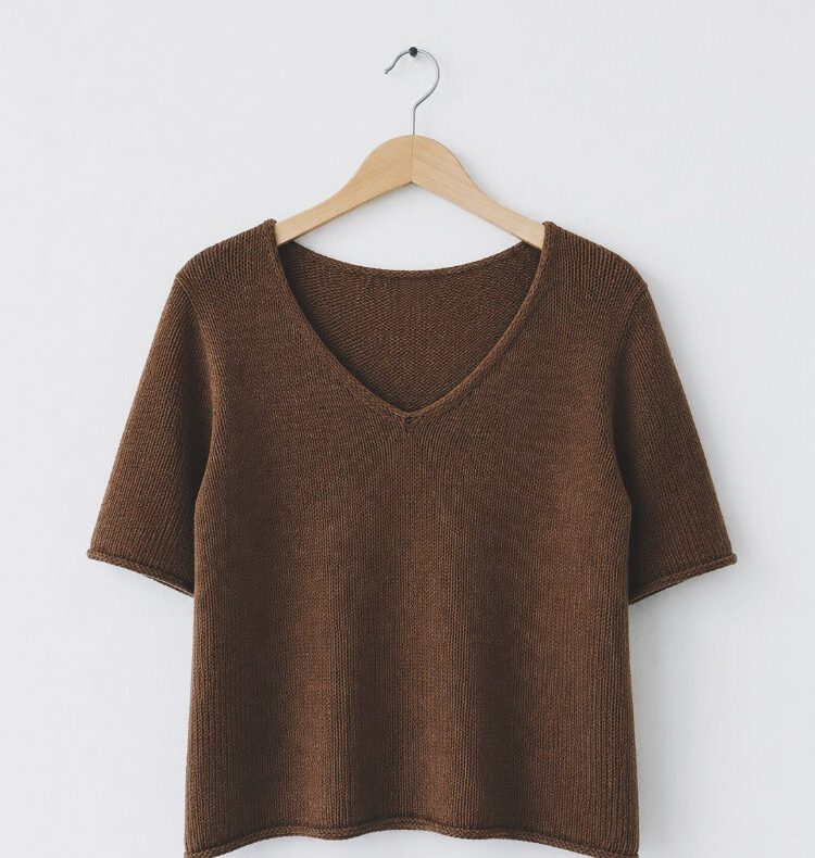 Uukii Shirt aus braunem Baumwollgarn an einer weißen Wand hängend