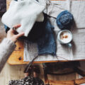 Strickszene mit Garn, Anleitung und Tasse auf Holztisch – Vorbereitung auf den rosa p. Knit-Along