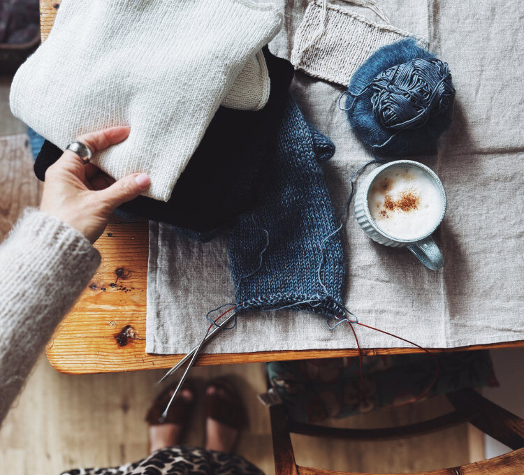 Strickszene mit Garn, Anleitung und Tasse auf Holztisch – Vorbereitung auf den rosa p. Knit-Along