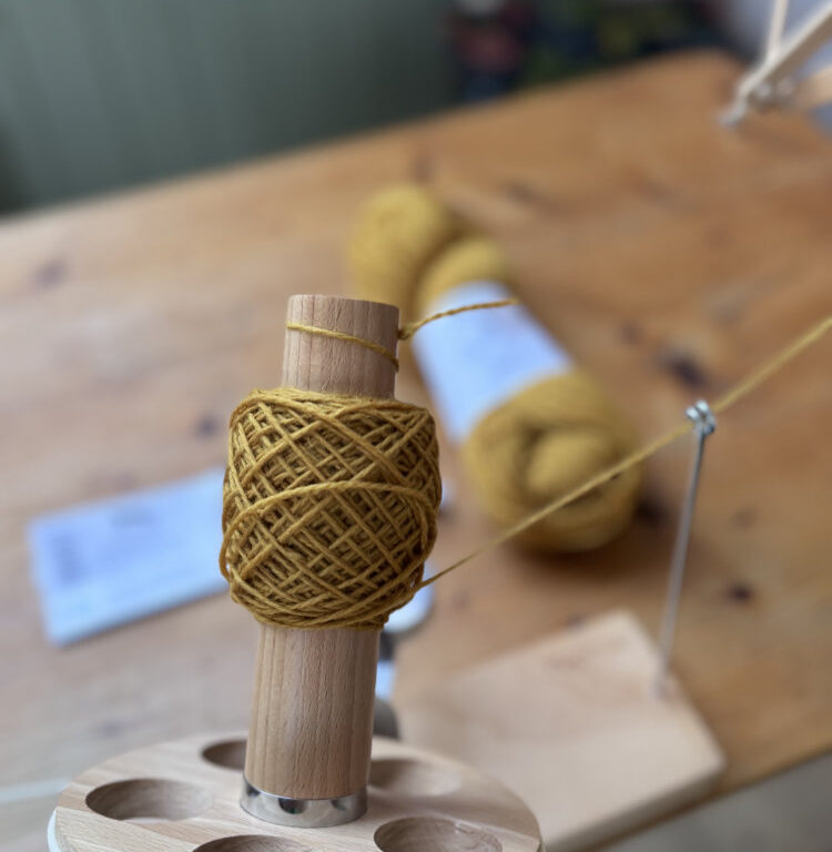 Strickgarn auf Wollwickler und Tisch – vorbereitetes Knäuel aus einem Strang, bereit zum Stricken