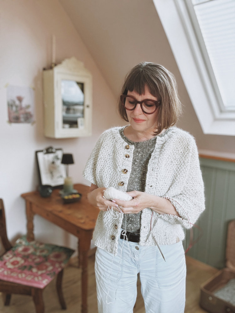 Frau trägt den Greetl Cardigan geschlossen über einer weißen Bluse