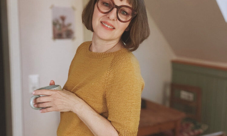 Frau trägt das gelbe Doorli Shortsleeve, gestrickt von oben nach unten – klassischer Look als Teil des Twinsets mit Cardigan
