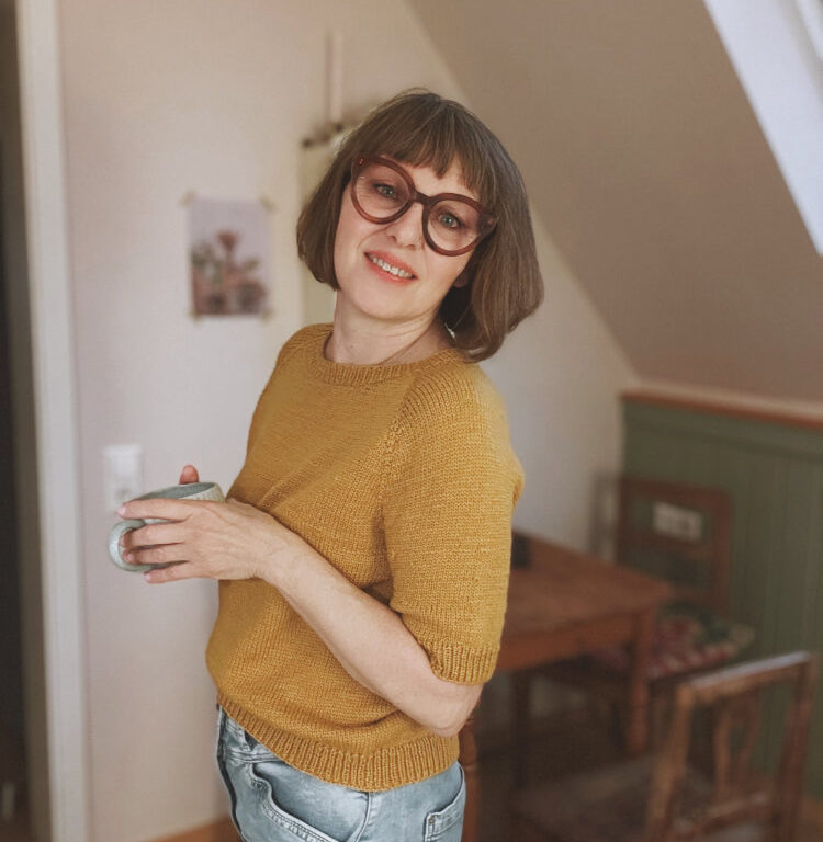 Frau trägt das gelbe Doorli Shortsleeve, gestrickt von oben nach unten – klassischer Look als Teil des Twinsets mit Cardigan