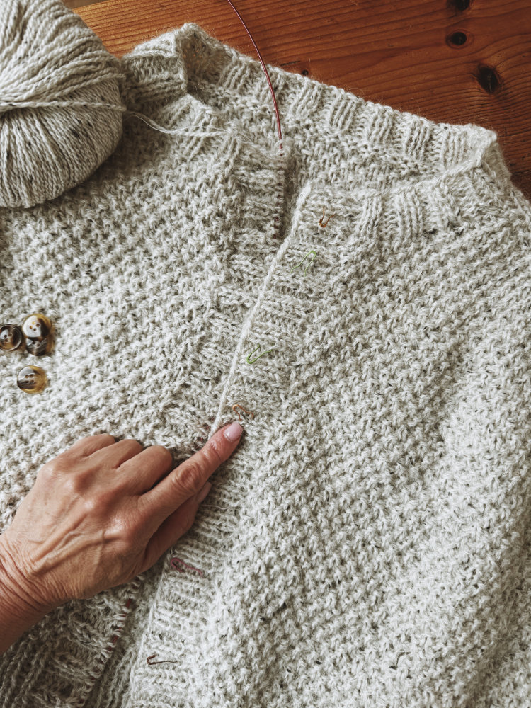 Nahaufnahme von Garn und Strickstück des Greetl Cardigans in Naturfarbe