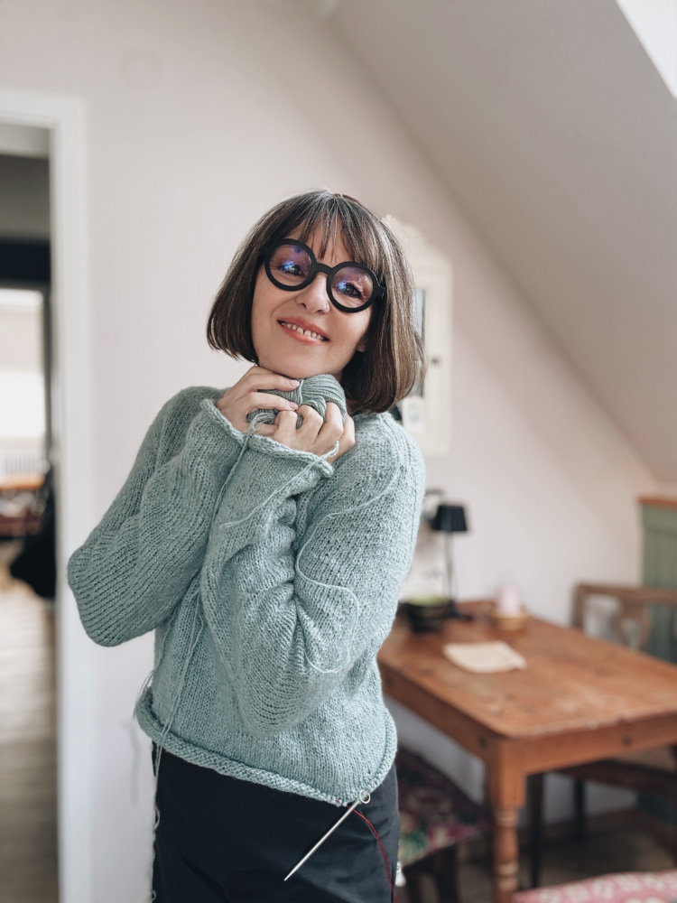 Uukii Sweater in sanftem Bau – nahtlos von oben nach unten gestrickt, mit Raglanärmeln und klarer, moderner Silhouette.