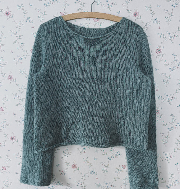 Uukii Sweater in hellem Grün, an der Wand hängend,