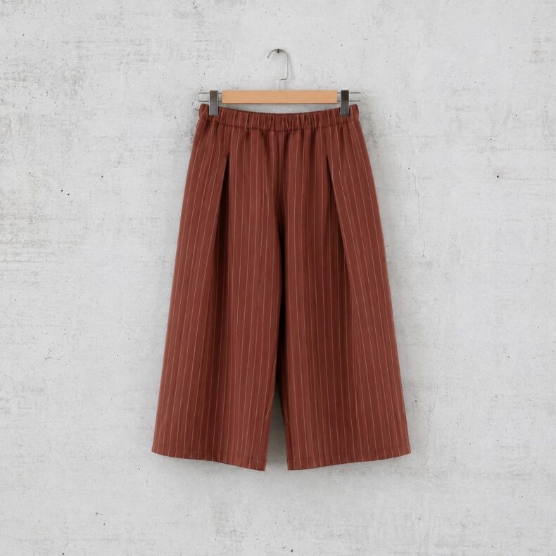 Pirkkoa Pants in braun mit weißen Streifen, an einer wand hängend