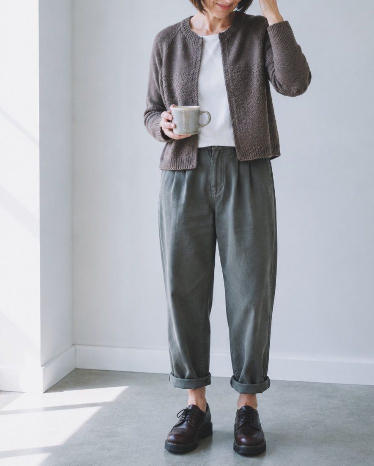 Kukka Cardigan aus braunem Meinogarn, getragen von einem Modell in einem hellen Raum